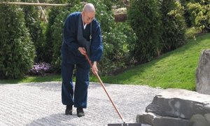 Japanischer Zen-Meister harkt Steinwege im Japanischen Garten in den Gärten der Welt
