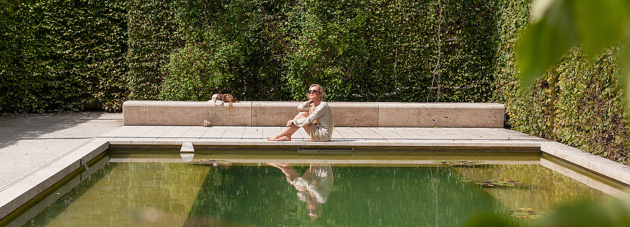 Eine Frau entspannt am Wasser im Gartenkabinett Libanon der Gärten der Welt
