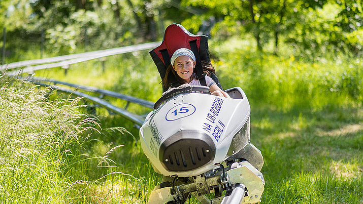 Mädchen fährt auf der Sommer-Bobbahn in den Gärten der Welt