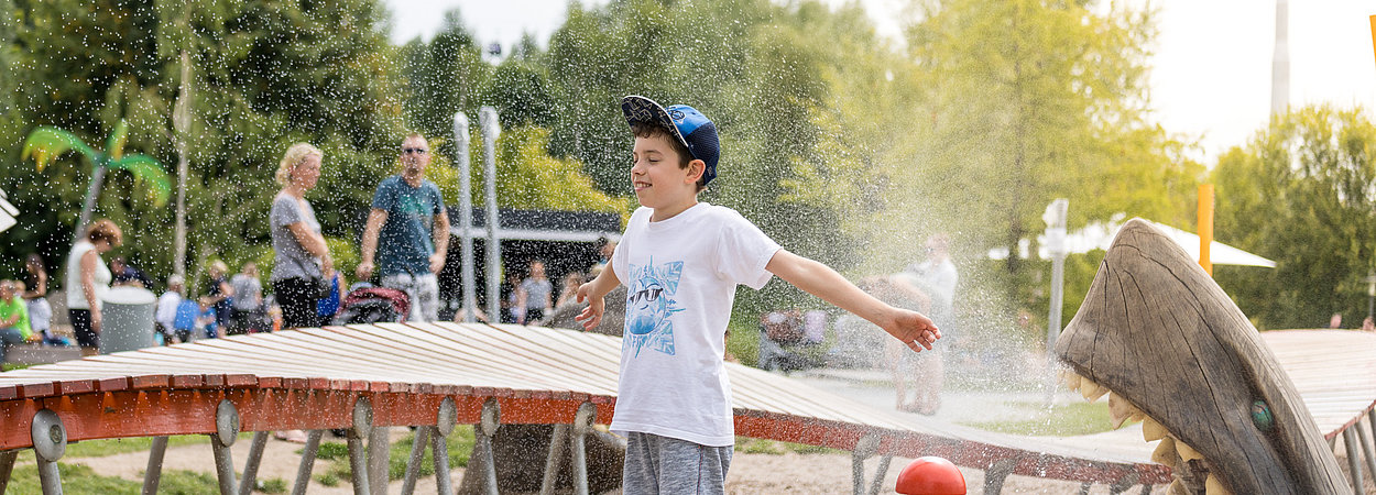 Kind spielt auf dem Wasserspielplatz in den Gärten der Welt