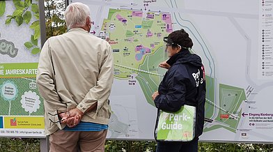 Ein Park-Guide hilft einem Park-Besucher in den Gärten der Welt